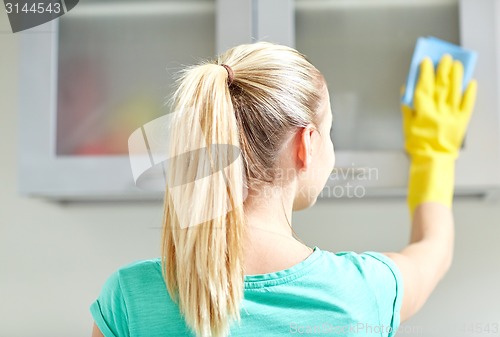 Image of happy woman cleaning cabinet at home kitchen