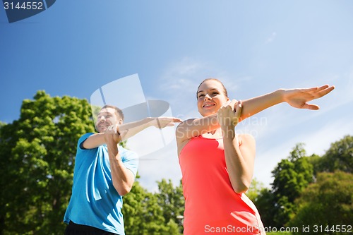 Image of smiling couple stretching outdoors