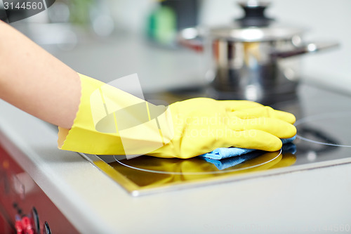 Image of close up of woman cleaning cooker at home kitchen