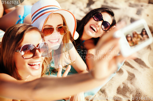 Image of girls making self portrait on the beach