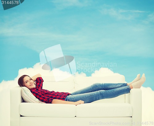 Image of smiling teenage girl lying on sofa