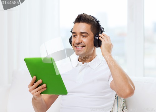 Image of smiling man with tablet pc and headphones at home