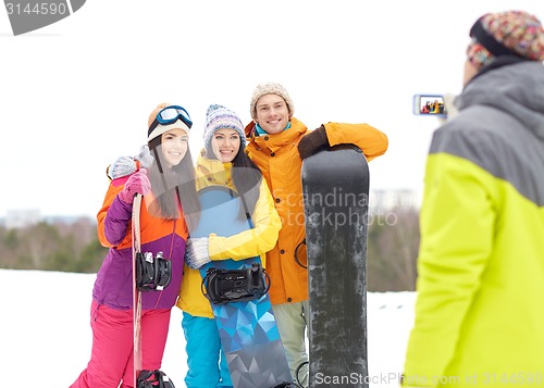 Image of happy friends with snowboards and smartphone