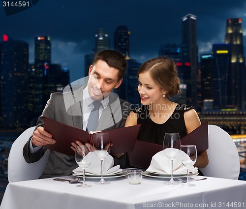 Image of smiling couple with menus at restaurant