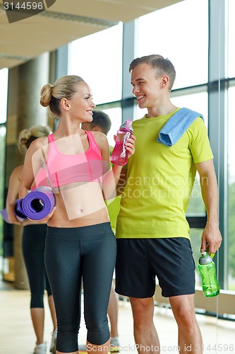 Image of smiling couple with water bottles in gym