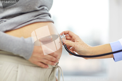 Image of close up of pregnant woman belly and doctor hand