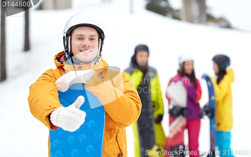 Image of happy young man with snowboard showing thumbs up