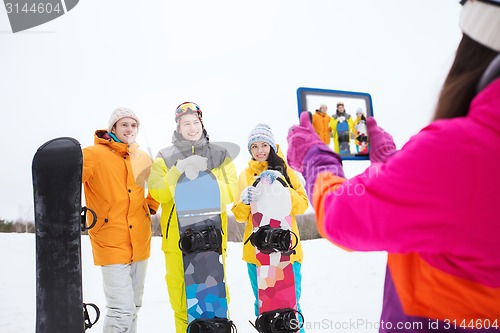 Image of happy friends with snowboards and tablet pc