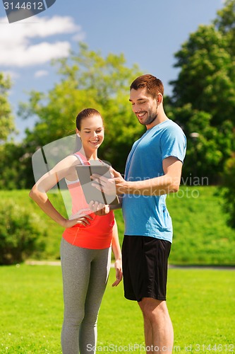 Image of smiling couple with tablet pc outdoors