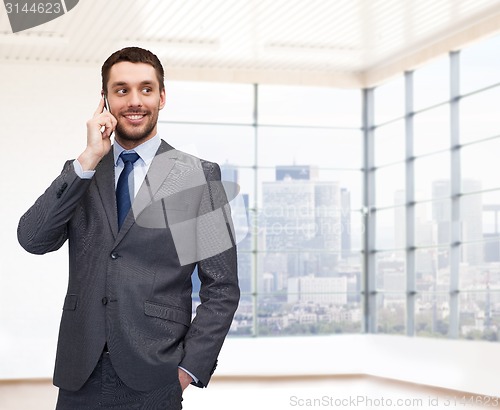 Image of happy young businessman calling on smartphone