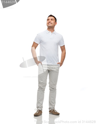 Image of smiling man with hands in pockets looking up