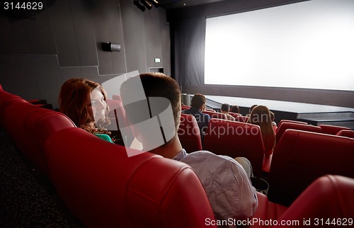 Image of happy couple watching movie and talking in theater