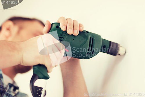 Image of man with electric drill making hole in wall