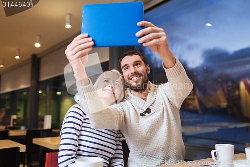 Image of happy couple with tablet pc taking selfie at cafe