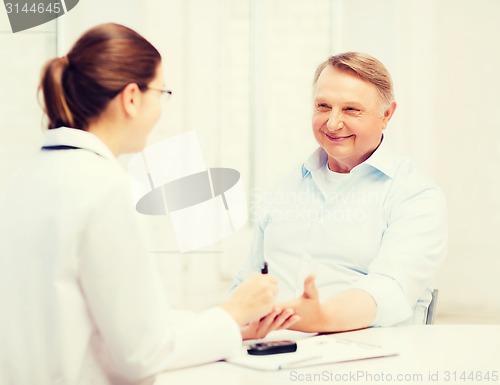 Image of female doctor or nurse measuring blood sugar value