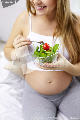 Image of close up of pregnant woman eating salad from bowl 