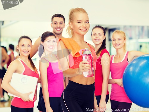 Image of smiling sporty woman with water bottle and towel