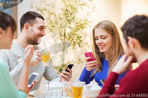 Image of group of friends with smartphones meeting at cafe