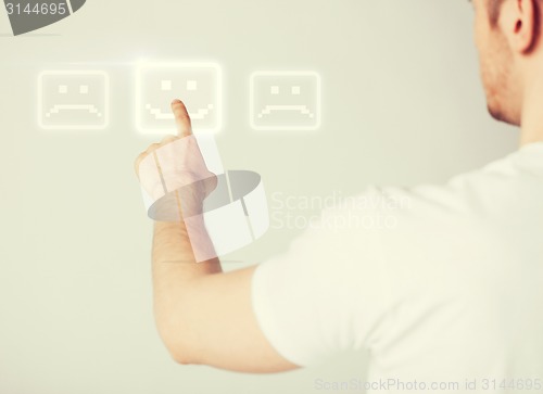 Image of hand touching virtual screen with smile button