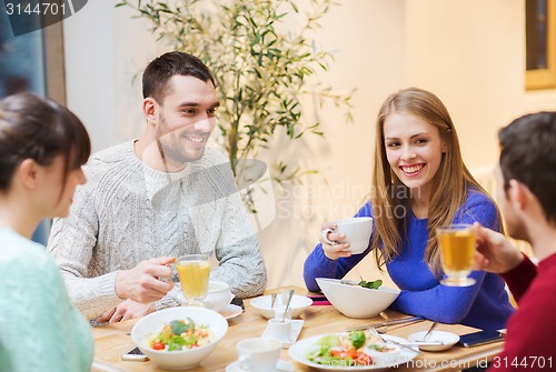 Image of happy friends meeting and having dinner at cafe