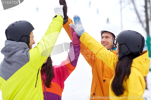 Image of happy friends in helmets making high five