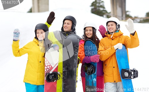 Image of happy friends in helmets with snowboards