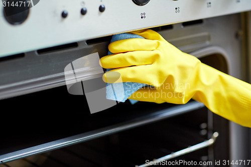 Image of close up of woman cleaning oven at home kitchen