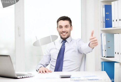 Image of smiling businessman with laptop and documents