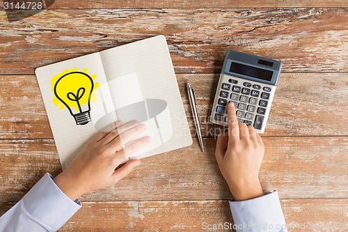 Image of close up of hands with calculator and notebook