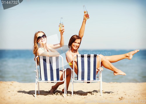 Image of girls sunbathing on the beach chairs