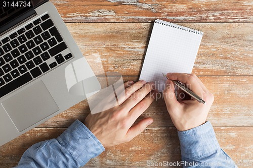 Image of close up of male hands with laptop and notebook