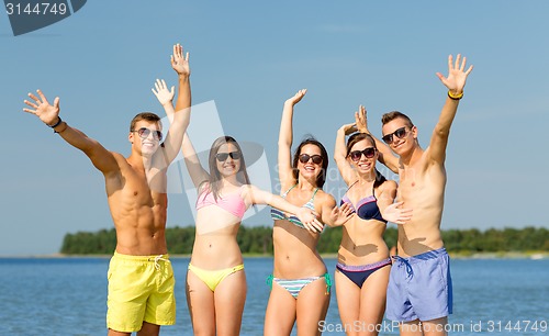 Image of smiling friends in sunglasses on summer beach