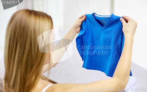Image of happy woman holding little boys pullover at home