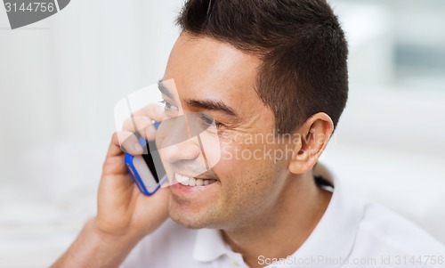 Image of happy man calling on smartphone at home