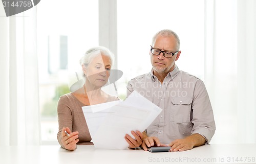 Image of senior couple with papers and calculator at home