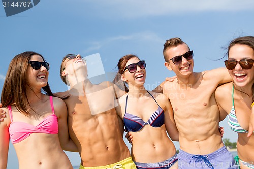 Image of smiling friends in sunglasses on summer beach