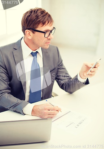 Image of businessman working with laptop and smartphone
