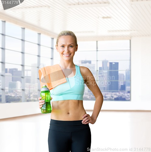 Image of happy woman with bottle of water and towel in gym