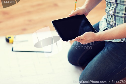 Image of male with tablet pc, blueprint and measuring tape