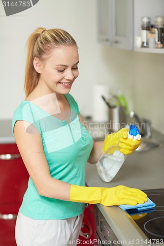 Image of happy woman cleaning cooker at home kitchen