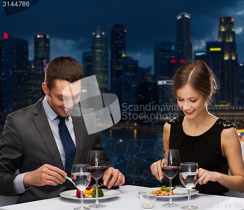 Image of smiling couple eating main course at restaurant