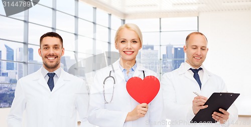 Image of happy young doctors cardiologists with red heart