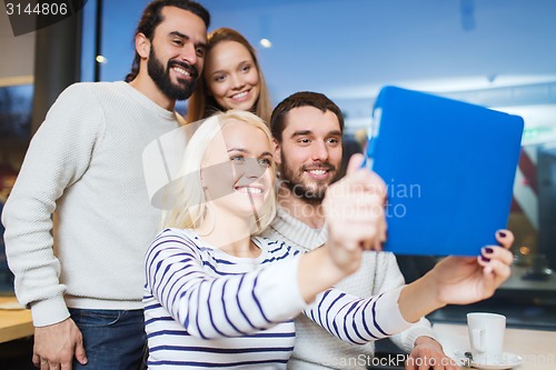 Image of happy friends with tablet pc taking selfie at cafe