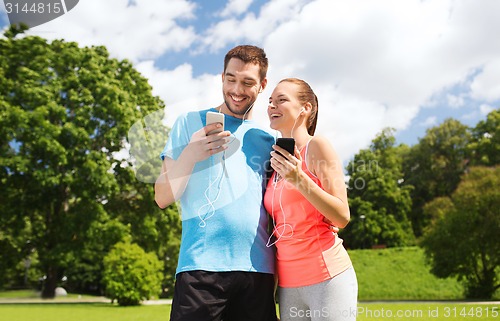 Image of two smiling people with smartphones outdoors