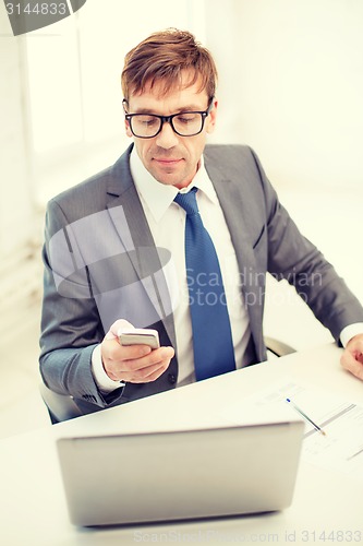 Image of businessman working with laptop and smartphone