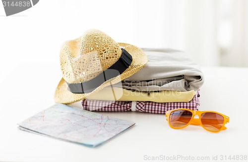 Image of close up of summer clothes and travel map on table