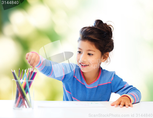 Image of happy little girl drawing with coloring pencils