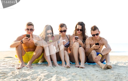 Image of friends with smartphones on beach