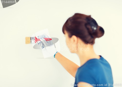 Image of woman with paintbrush colouring the wall