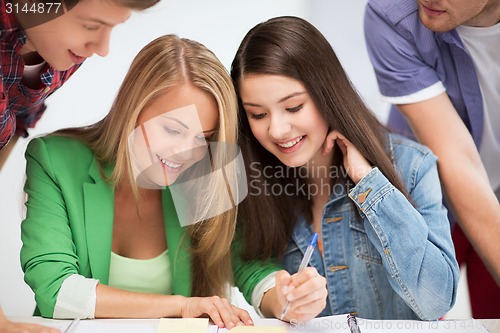 Image of students pointing at notebook at school